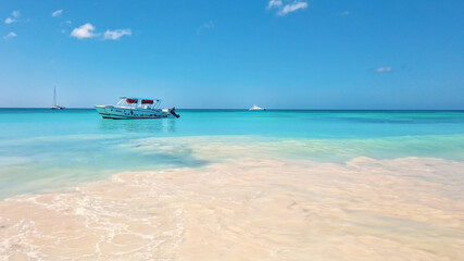 Obraz premium Ship floating in bright turquoise water. View of endless sea in tropical destination. Exotic vacation in Dominican Republic.