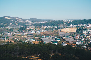 Panorama landscape, Dalat city, Langbian Plateau, Vietnam Central Highland region. Vegetable fields, many houses, architecture, farmlands, greenhouses. Forested Mountain background. Evening photo