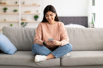 Closeup of smiling woman using smartphone at home
