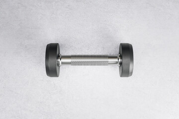 Sport and workout concept with stylish black dumbbell in the center of concrete floor backdrop