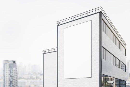 Blank Vertical White Outdoor Billboard On Brick Wall Of Modern Building At Blurry City Background. 3D Rendering, Mockup