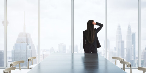 Pensive businesswoman thinking about future and looking at megapolis city through big window in modern meet room