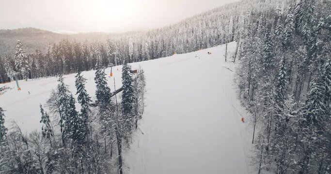 Ski resort with people at pine forest aerial. Tourists snowboarding down the hill at sunrise. White snow covered fir trees in winter season. Sport lifestyle. Nature landscape. Travel to Andora, Europe