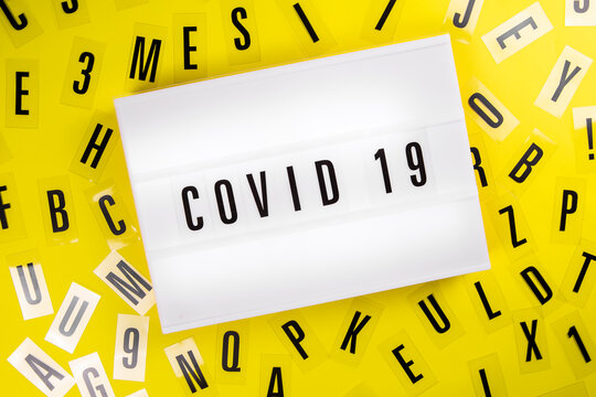 Lightbox with text COVID 19 on yellow background with black letters randomly scattered. Concept of coronavirus pandemic, worldwide lockdown, medical research news, vaccination, analytics, statistics