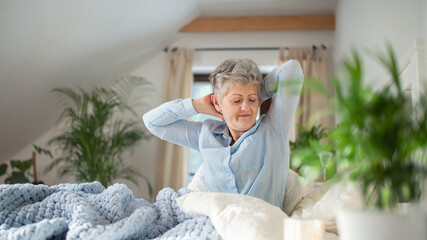 Senior woman in bed at home getting up in the morning.