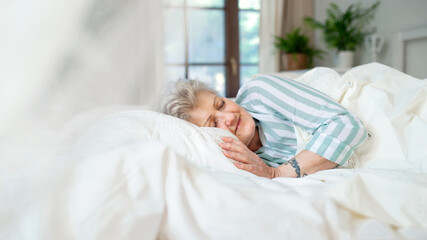 Obraz na płótnie Canvas Happy senior woman in bed at home, sleeping.