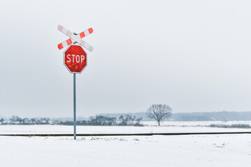 Red stop sign and St. Andrew's cross in front of an unguarded railway crossing.