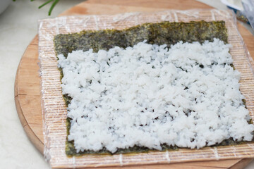 Cook's hands close-up. A chef makes sushi and rolls from rice, red fish, avocado and philadelphia cheese. step by step. step 4.