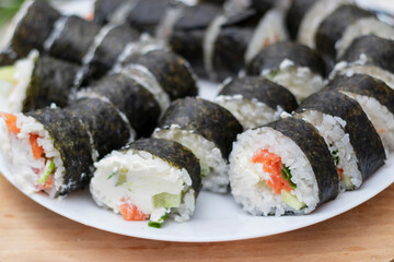 Preparing, rolling sushi and rolls from rice, red fish, avocado and philadelphia cheese.