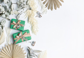 Beautiful flat-lay gift arrangement decorated by dried flowers including; Ruscus leaves, Palm Fronds, gum nuts, Amaranthus and Eucalyptus leaves, on a white background. 