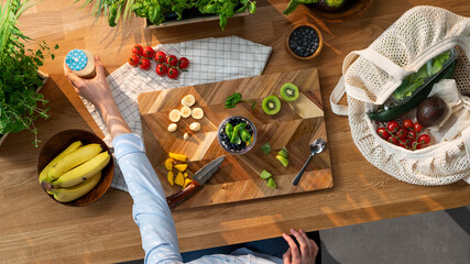 Top view of unrecognizable woman preparing fruit smoothie, sustainable lifestyle.
