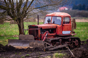 An old caterpillar bulldozer during work on leveling the ground. Made on a cloudy day, poor lighting conditions © Fotoforce