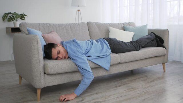 Apathy and disinterest. young depressed caucasian guy lying on sofa at home, feeling stress and indifference
