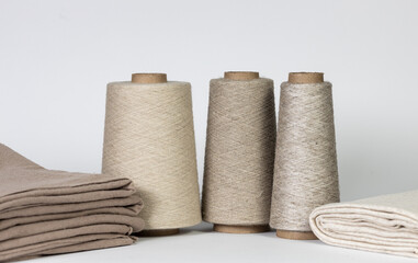 Close-up of bobbins with linen threads near the bed linen. Isolated on white with copy space