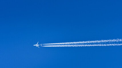 A passenger plane flies at high altitude and leaves a condensation trail behind it.