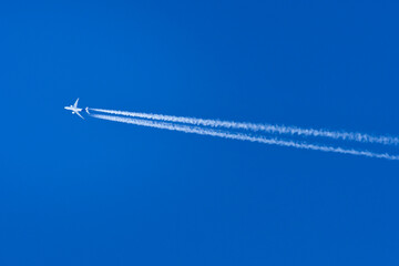 A passenger plane flies at high altitude and leaves a condensation trail behind it.