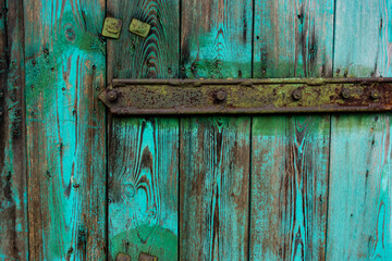 Old, green, wooden doors to farm buildings, with steel fittings. Poor lighting conditions