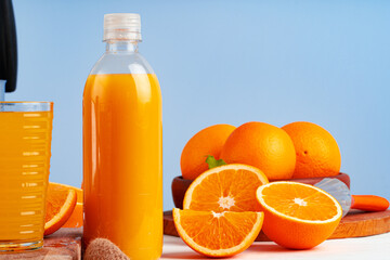 Bottle of orange juice and fresh oranges on table