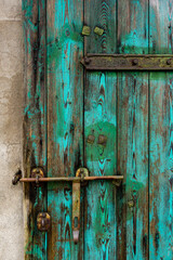 Old, green, wooden doors to farm buildings, with steel fittings. Poor lighting conditions
