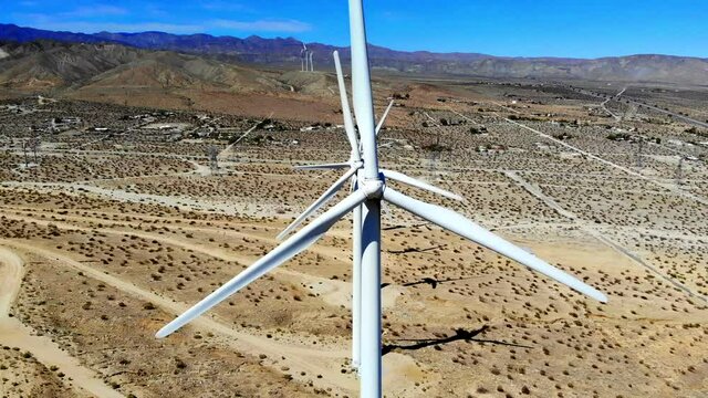 Windmills, wind turbines, aerial 4k drone slow pull back from shot down line of spinning blades, energy, green, renewable, power generating farm on desert hills, Palm Springs, Coachella, Cabazon, CA