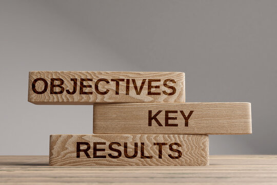 Wood cubes with acronym 'OKR' - 'Objectives and Key Results' on a beautiful wooden table, studio background. Business concept and copy space.