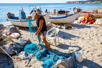 Fisher pile up fishing net at sandy beach