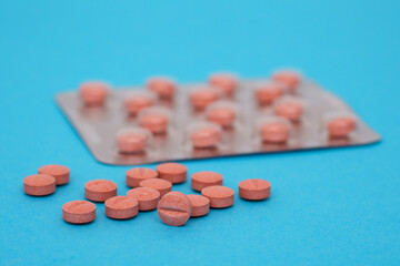 Medical pills in terracotta color on a blue background. Close up.