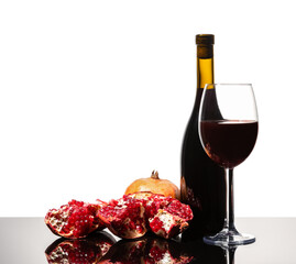 Isolated wine bottle, wine glass and juicy pomegranate on a white background