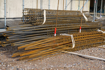 A bunch of metal reinforcement lying near a building under construction.