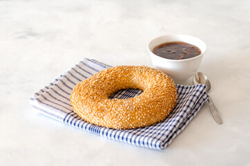 Turkish simit of homemade traditional Turkish pastries. Turkish crispy round braided bagels with sesame seeds. Served on a linen napkin with jam and tea. Close up. Copy space.