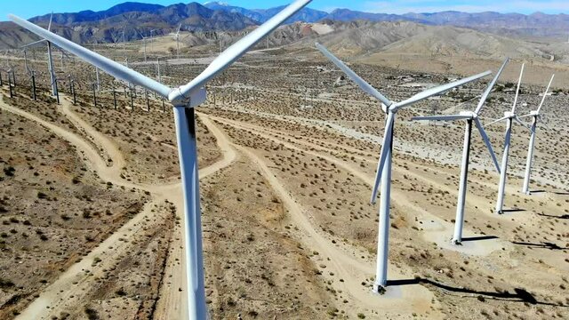 Windmills, wind turbines, aerial 4k drone slow pull back, energy, green, renewable, huge power generating farm on desert hills, Mt San Gorgonio in BG in Palm Springs, Coachella Valley, Cabazon, Calif.