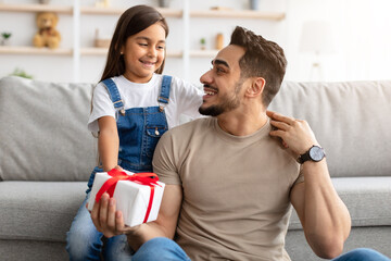 Girl celebrating father's day, greeting excited dad with present