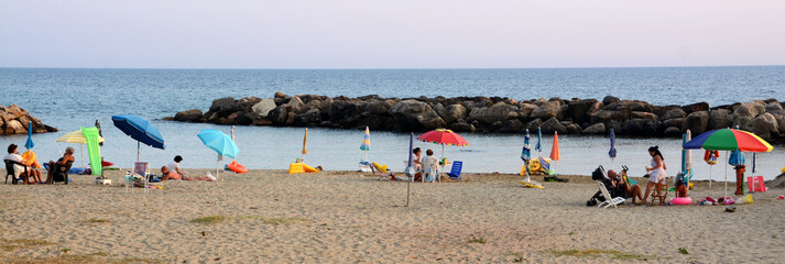 Tourists on a beach of Cilento at sunset relaxed after a day of sea, swimming and swimming during...