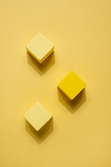 Yellow geometrical figures still life composition. Wooden game cube objects on yellow background. Platonic solids figures, simplicity concept