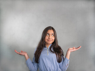 Smiling young woman in blue striped jersey, the elbows bent, arms raised and palms up. The face...