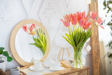 Home decor with bouquet of spring tulips in vase and tea set on table indoors, copy space