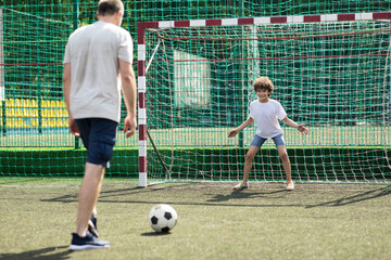 Man teaching his son how to play soccer outdoors