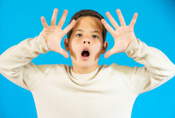 Surprised little boy in casual sweater isolated over blue background