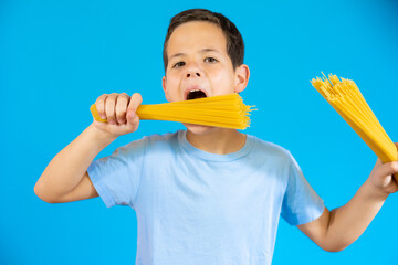 Cute smiling boy holding traditional Italian spaghetti in his hands.