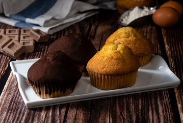 Chocolate and sugar muffin on white tray on dark wooden table