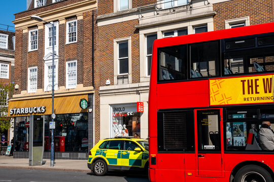 Red London Double Deck Bus Passing A Parked First Responder Ambulance On A High Street