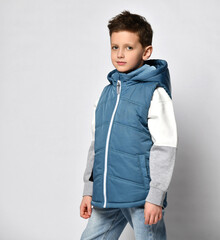 teenage boy wearing a blue down jacket, down jacket without sleeves with zipper and jeans. on white...