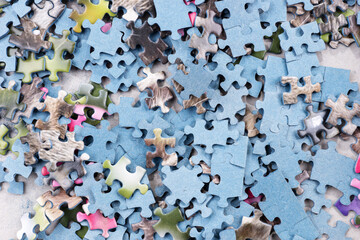 Many pieces of an unfinished puzzle. Pile of jigsaw puzzle pieces