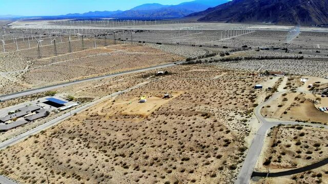 Fly in across barren desert part 3, Interstate 10 freeway, windmills, wind turbines energy, green, renewable, huge power generating farm, Palm Springs, Coachella Valley, aerial 4k drone, Cabazon, CA