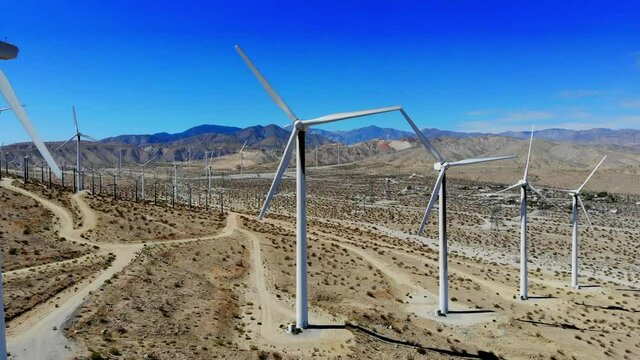 Windmills, wind turbines- aerial 4k drone right to left tracking shot, energy, green, renewable, huge power generating farm on desert hills,  Mt. San Gorgonio in BG, Palm Springs, Coachella, Cabazon