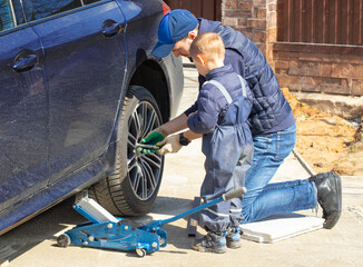 Father and son are fixing the car. The son helps the dad. Happy Father's Day. 