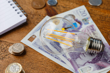 counting monthly expenses, electricity bills, money and payments, doing paperwork with energy efficient led filament Lightbulb Glowing, Devon, United Kingdom April 19 2021