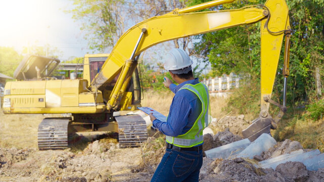 Civil engineer working inspection on site while backhoe working