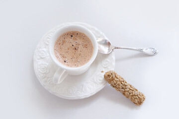 closeup of cappuccino coffee in a white cup and saucer on a white background with a spoon, cookies, cafe menu concept, coffee time, danger of caffeine, addiction