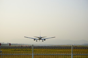 Fototapeta na wymiar Airplane landing on runway at the airport - 着陸する飛行機 後ろ姿 飛行場